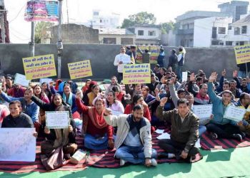 बारिश के बावजूद धरना स्थल पर डटे रहे बर्खास्त कार्मिक।